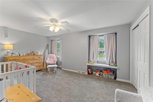 bedroom with ceiling fan, a closet, carpet, and a crib