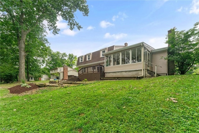 back of house featuring a sunroom, a deck, and a lawn