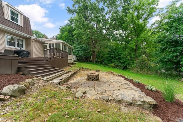 view of yard with a sunroom, an outdoor fire pit, and a wooden deck