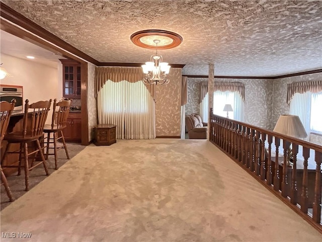 interior space with carpet, ornamental molding, a textured ceiling, and an inviting chandelier