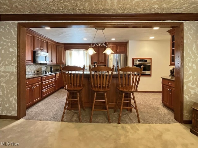 kitchen with light carpet, appliances with stainless steel finishes, a kitchen bar, tasteful backsplash, and decorative light fixtures