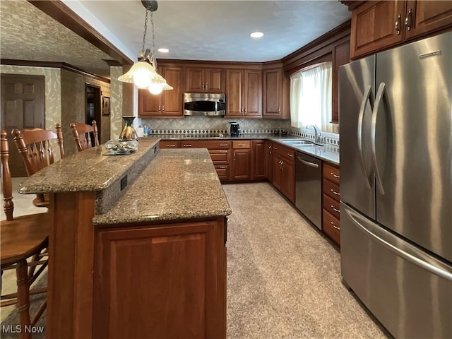 kitchen featuring a breakfast bar, appliances with stainless steel finishes, stone counters, and hanging light fixtures