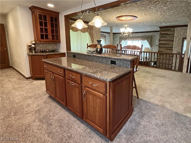 kitchen featuring light carpet, dark stone counters, a breakfast bar, decorative light fixtures, and a chandelier