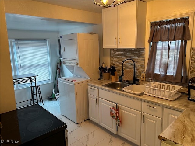 clothes washing area featuring stacked washer and clothes dryer and sink