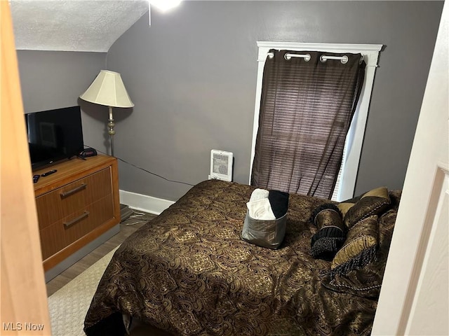 bedroom featuring a textured ceiling, heating unit, and lofted ceiling