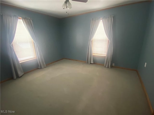 carpeted spare room featuring ceiling fan and a wealth of natural light