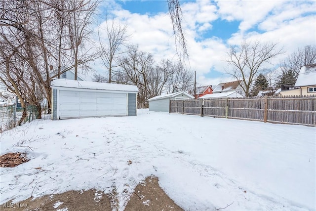 yard covered in snow with a garage and an outdoor structure