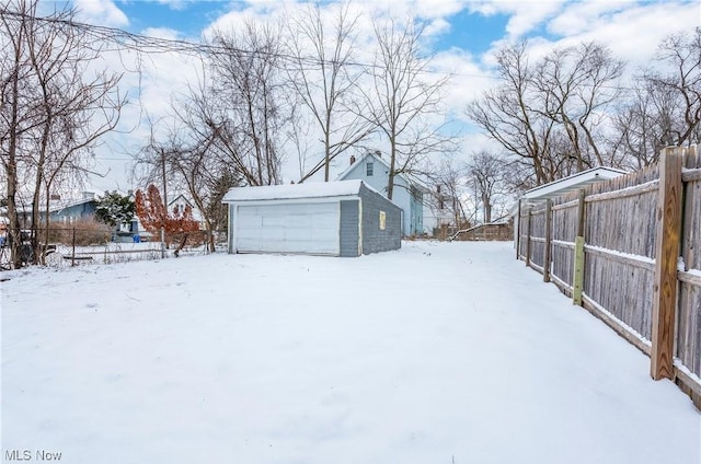 snowy yard featuring a garage and an outdoor structure