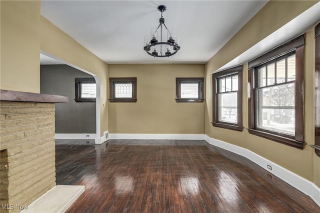 unfurnished dining area with dark wood-type flooring and an inviting chandelier