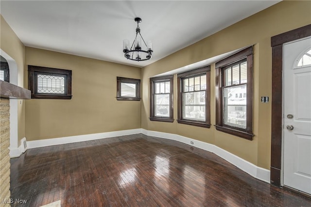 unfurnished dining area with a chandelier and dark wood-type flooring