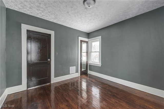 unfurnished room featuring wood-type flooring and a textured ceiling