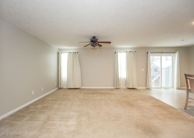 carpeted spare room featuring a textured ceiling and ceiling fan