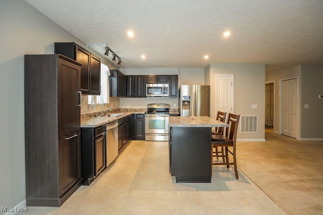 kitchen featuring light colored carpet, sink, a kitchen island, a kitchen bar, and stainless steel appliances