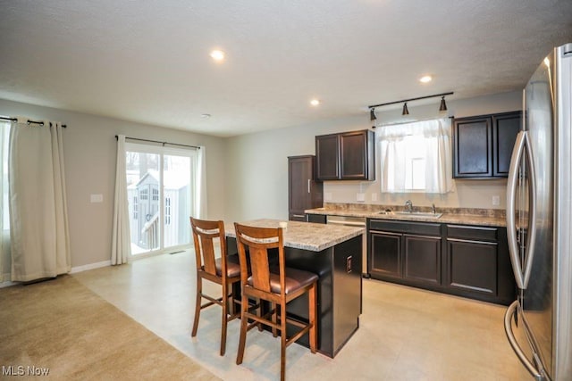 kitchen featuring a center island, rail lighting, sink, a breakfast bar area, and stainless steel refrigerator