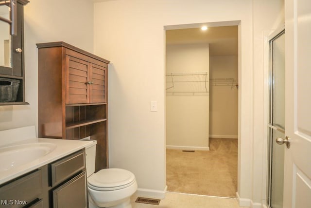 bathroom with vanity, toilet, and a shower with shower door