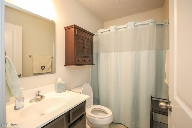 bathroom with vanity, a textured ceiling, toilet, and walk in shower