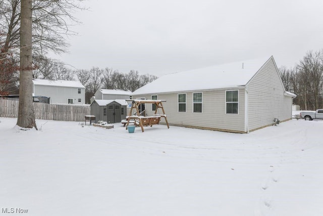 snow covered property with a storage shed