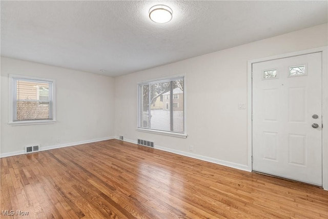 foyer entrance featuring a textured ceiling and light wood-type flooring