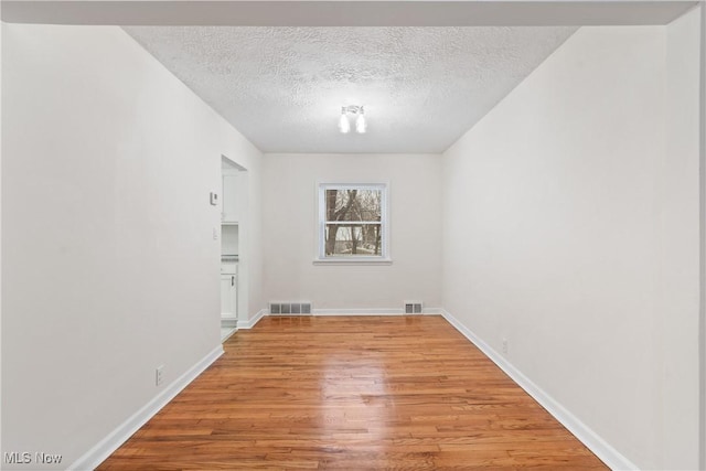 empty room featuring a textured ceiling and light hardwood / wood-style flooring