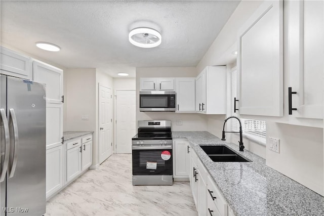 kitchen featuring light stone countertops, sink, stainless steel appliances, a textured ceiling, and white cabinets