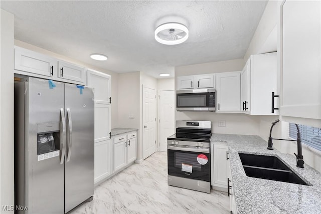 kitchen featuring white cabinetry, sink, stainless steel appliances, and light stone counters