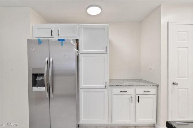 kitchen featuring stainless steel fridge and white cabinets