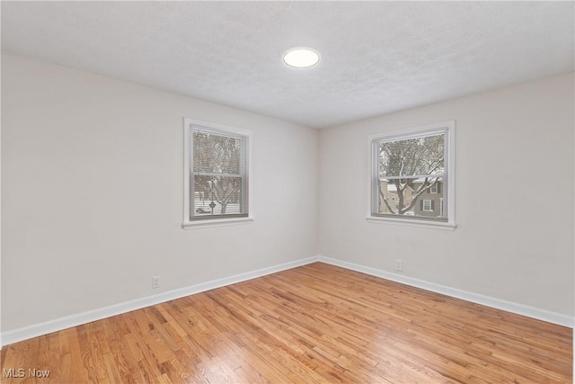 unfurnished room with light wood-type flooring and a textured ceiling