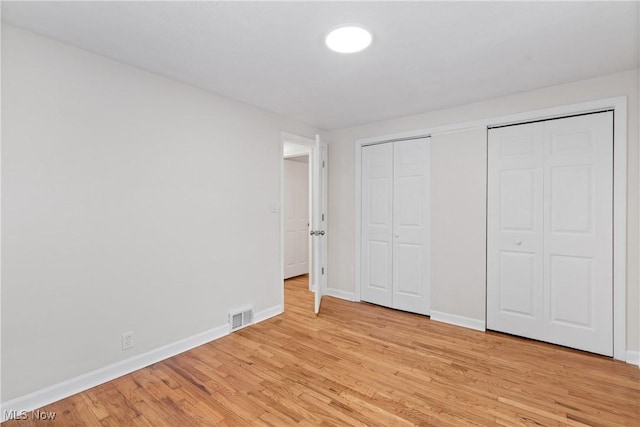 unfurnished bedroom with light hardwood / wood-style floors and two closets