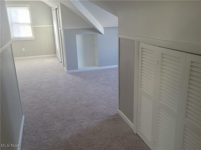 additional living space featuring lofted ceiling and light carpet