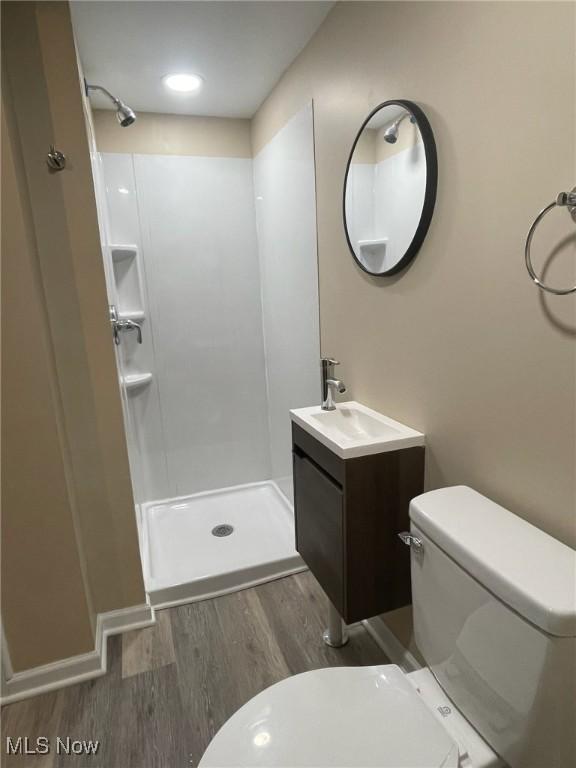 bathroom featuring hardwood / wood-style floors, vanity, toilet, and a shower