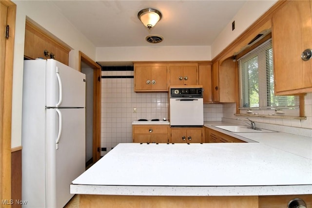 kitchen featuring kitchen peninsula, decorative backsplash, white appliances, and sink