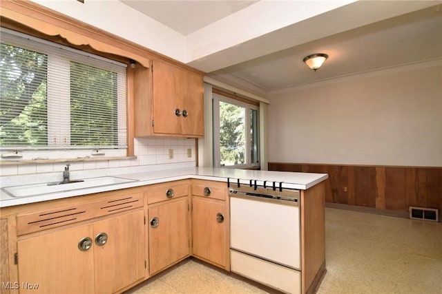 kitchen featuring kitchen peninsula, ornamental molding, white dishwasher, sink, and wood walls