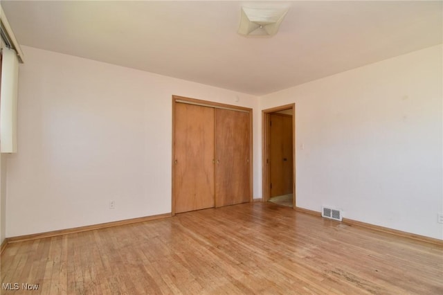 unfurnished bedroom featuring light wood-type flooring and a closet