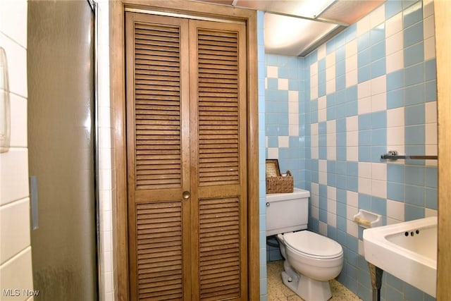 bathroom with sink, toilet, and tile walls