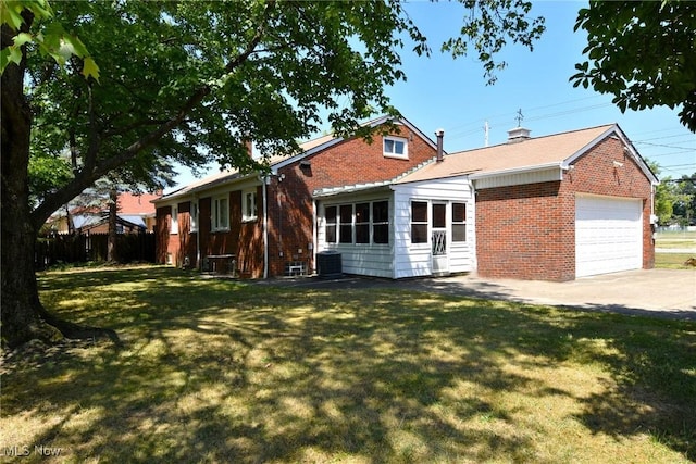 back of property with a lawn, central AC unit, and a garage