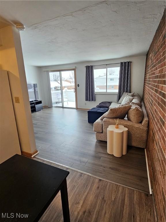 living room featuring wood-type flooring and brick wall