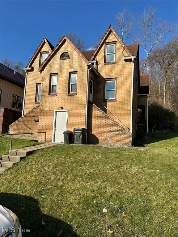 rear view of property featuring a lawn