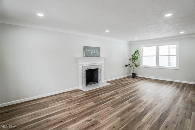 unfurnished living room featuring wood-type flooring, a textured ceiling, and a premium fireplace