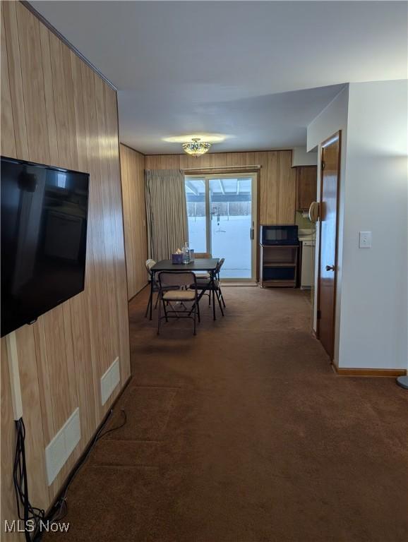 dining room with dark carpet and wooden walls