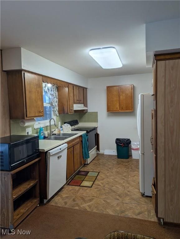 kitchen featuring decorative backsplash, white appliances, and sink