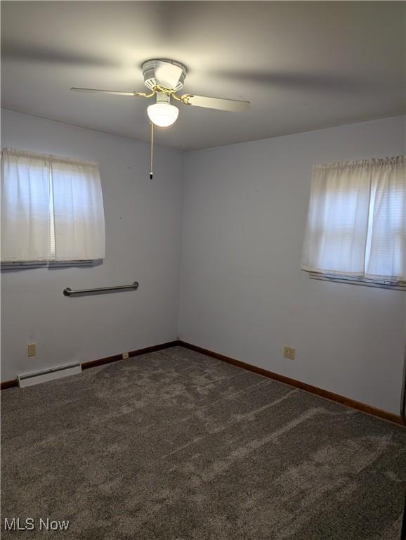 carpeted empty room featuring ceiling fan and a baseboard heating unit