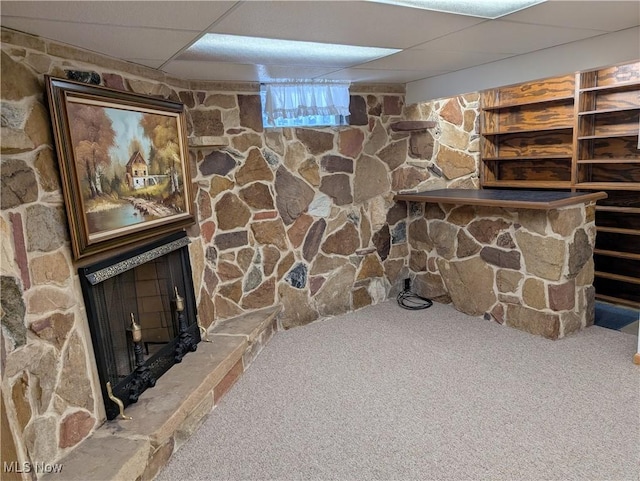 interior space with carpet flooring, a drop ceiling, and a fireplace