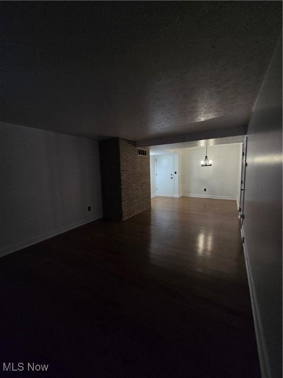 spare room featuring dark hardwood / wood-style floors and a textured ceiling