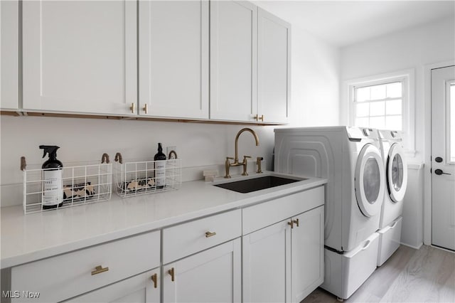 washroom featuring cabinets, independent washer and dryer, sink, and light wood-type flooring