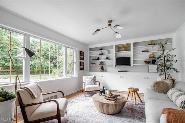 living room featuring hardwood / wood-style flooring, built in features, and a chandelier