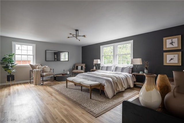 bedroom with light wood-type flooring and an inviting chandelier