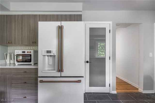 kitchen with decorative backsplash, dark tile patterned floors, and high end white refrigerator