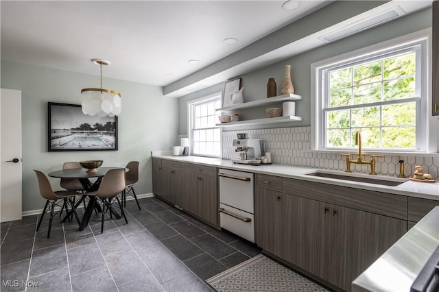 kitchen with sink, hanging light fixtures, dark tile patterned floors, decorative backsplash, and dark brown cabinets