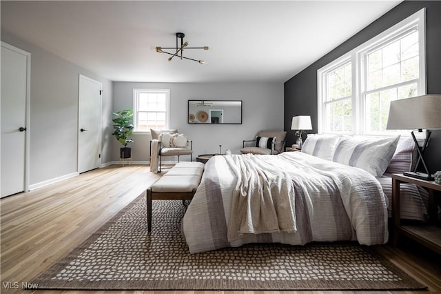 bedroom with light hardwood / wood-style floors and an inviting chandelier