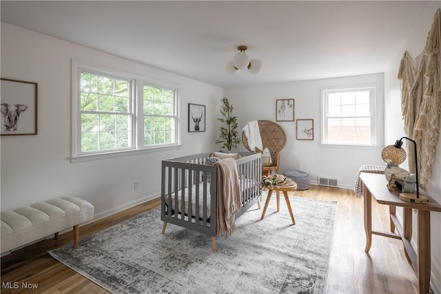 bedroom with a nursery area and light hardwood / wood-style floors